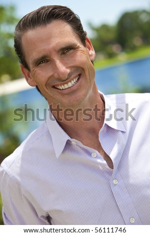 An outdoor portrait of smiling handsome middle aged man shot with sunlight against a natural background with a lake