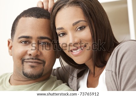 A happy African American man and woman couple in their thirties sitting at home