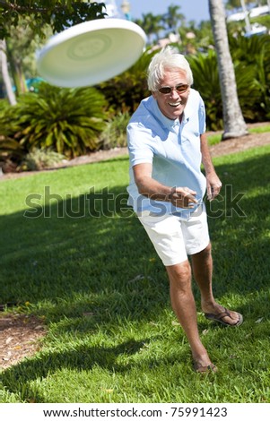 Happy Senior Man Throwing A Frisbee Outside In A Park In Sunshine Stock ...