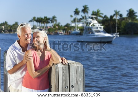 Happy senior man and woman couple together by a river or sea in a tropical location with a boat sailing past