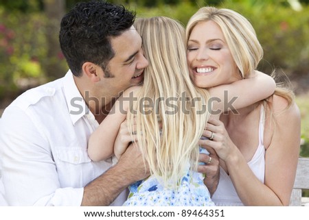 A young girl hugging her happy mother and father parents outside in a park or garden