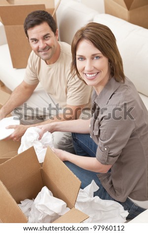 Happy couple in their thirties unpacking or packing boxes and moving into a new home.