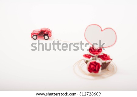 a red toy car with roses and a heart-shape card