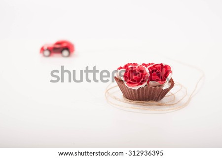 a red toy car is carrying some roses