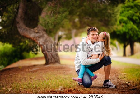 happy young family father and baby daughter hugging and smiling at beautiful park in summer day