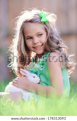 Cute little girl with a bunny rabbit has a easter at green grass background