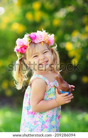 happy easter girl eat chocolate bunny at meadow background