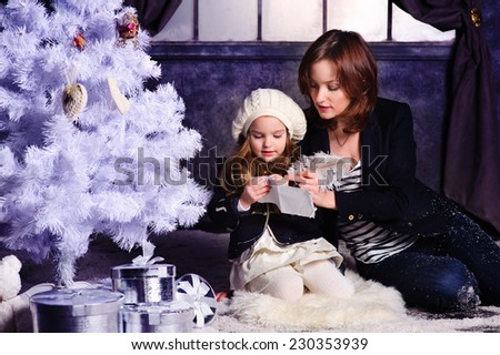 Young beautiful mother and her cute daughter writing a letter to Santa Claus
