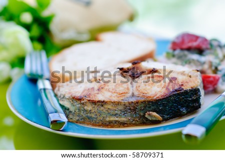dish served with fried tuna and salad with a knife and fork on the table with flowers