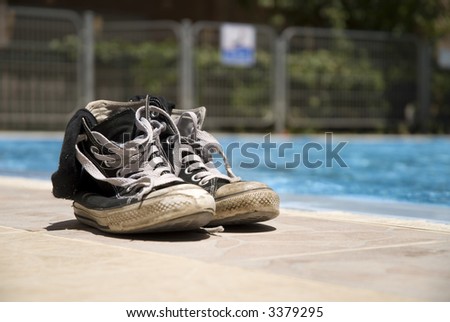 Pair of old shoes on edge of a pool