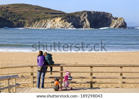 BASQUE COUNTRY, SPAIN - DECEMBER 08, 2011: Lovely view of a mother and daughter together watching the beach in winter in the Basque Country, Spain on Dec 08, 2011