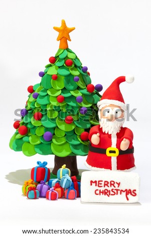 Santa Claus handmade with modeling clay wishing Merry Christmas with a Christmas tree and presents