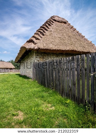 Farmstead with thatched cottage and picket fence shot against blue sky
