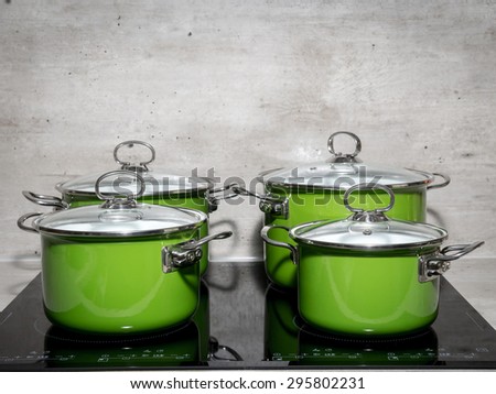 Four green enamel stewpots on black induction cooker