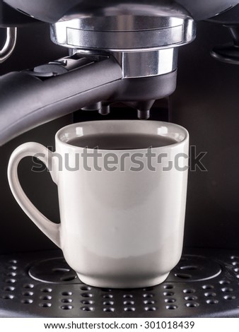 Closeup of modern coffee machine with white mug filled with hot coffee