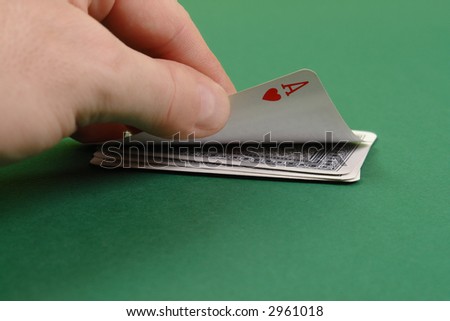 Gambler hand revealing ace of hearts on green table