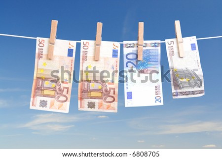 Fifty, twenty and five euro banknotes hanging on laundry line attached with wooden clips over blue sky
