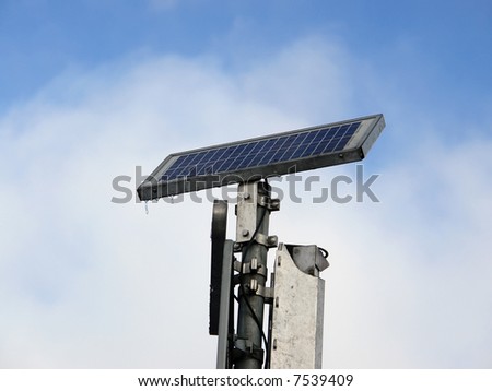 Ice-covered solar cell panel powering street traffic lights over blue sky