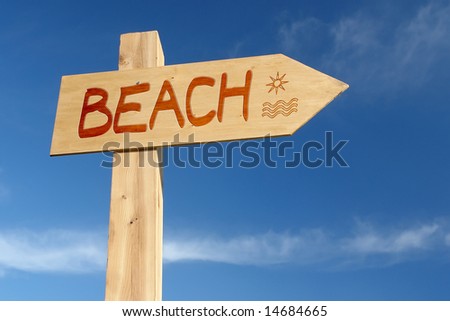 Wooden signpost indicating Beach direction over blue sky