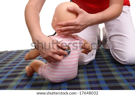 First aid instructor using infant dummy to demonstrate how to examine baby with stethoscope