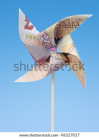 British Pound banknote cut into toy windmill shot on blue background