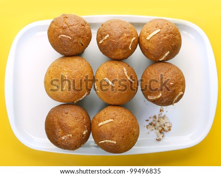 Nine cupcakes on plate and crumbs from one that has been eaten - shot from above