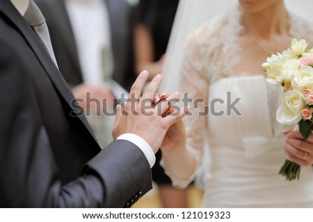 bride puts wedding ring on groom\'s finger