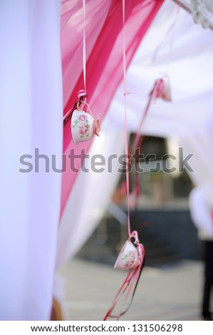 empty cups hanging on pink ribbons
