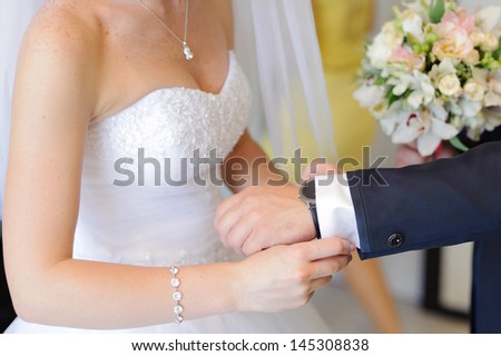 bride helping groom in wedding preparation