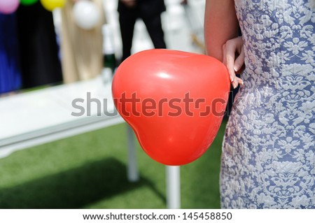 woman holding red balloon in form of heart