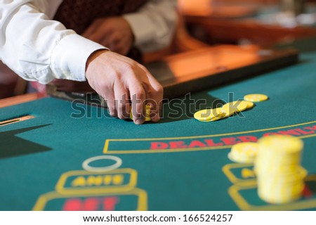 male hand holding yellow chips on green table