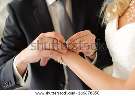 groom clasping snap of bride\'s bracelet