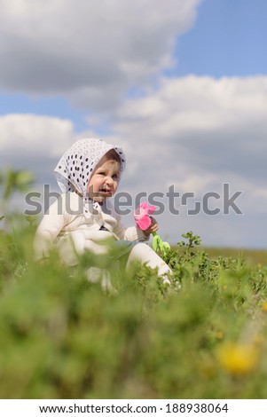 funny girl sitting in grass with toy flower
