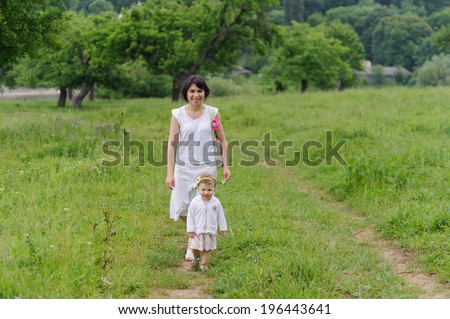 mother and daughter walking in meadow