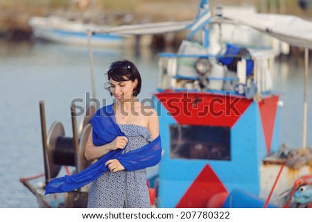 young woman in flying blue scarf on pier