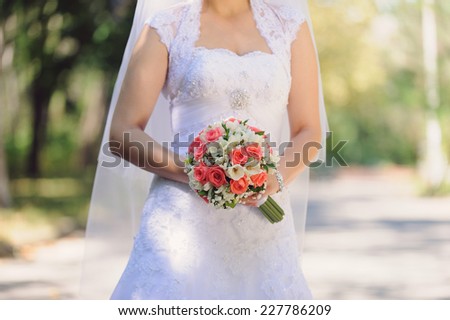 bride holding rose bouquet in park