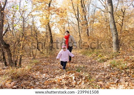 mother running after her daughter on dry leaves