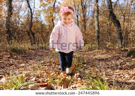 smiling girl walking in park on dry leaves