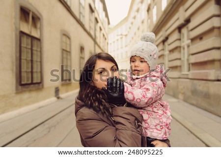 mother kissing daughter\'s hand in street