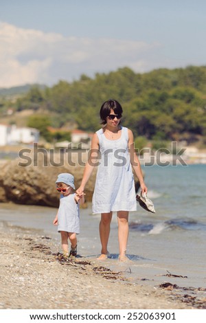 woman with girl walking along seashore