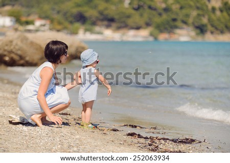 mother holding baby who throw stone in water