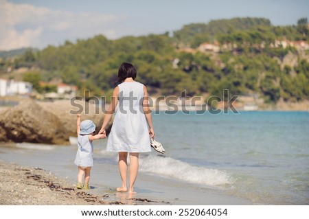 mother and daughter walking away on beach