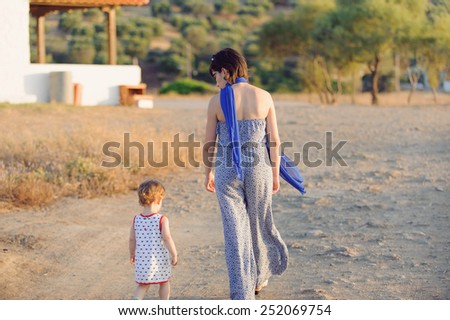 mother and daughter walking on beach at sunset