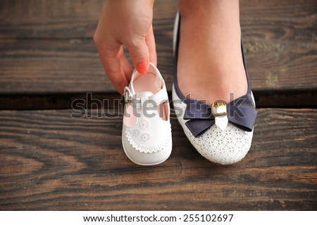 mother is holding child\'s shoe close to her own