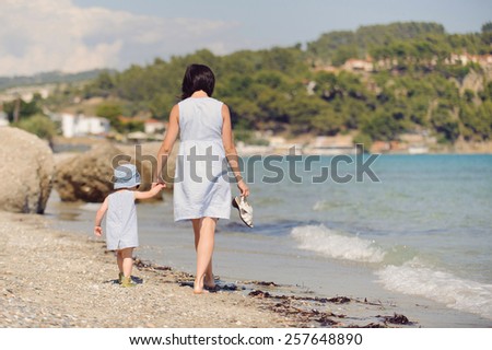mother and daughter walking on beach at sunny day