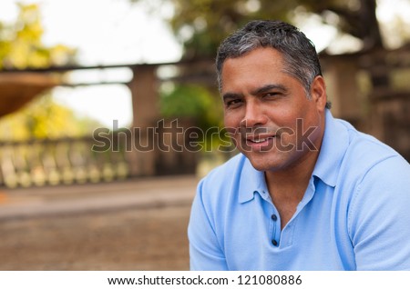 Handsome middle age Hispanic man in casual clothing outdoors.