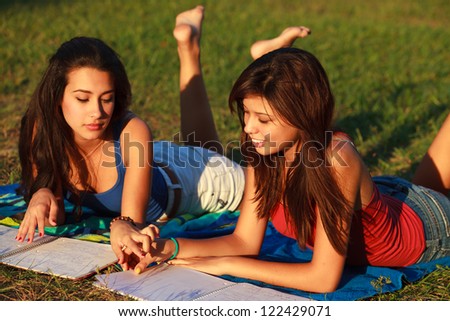 Beautiful multicultural young college women studying outdoors on campus.