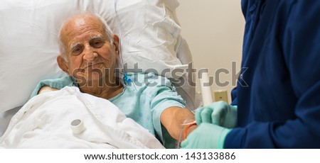 Elderly eighty plus year old man recovering from surgery in a hospital bed.