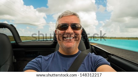 Handsome middle age man driving a convertible automobile on the highway.