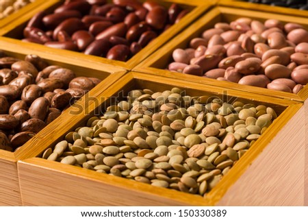 Close up view of a collection of various beans contained in wood boxes.